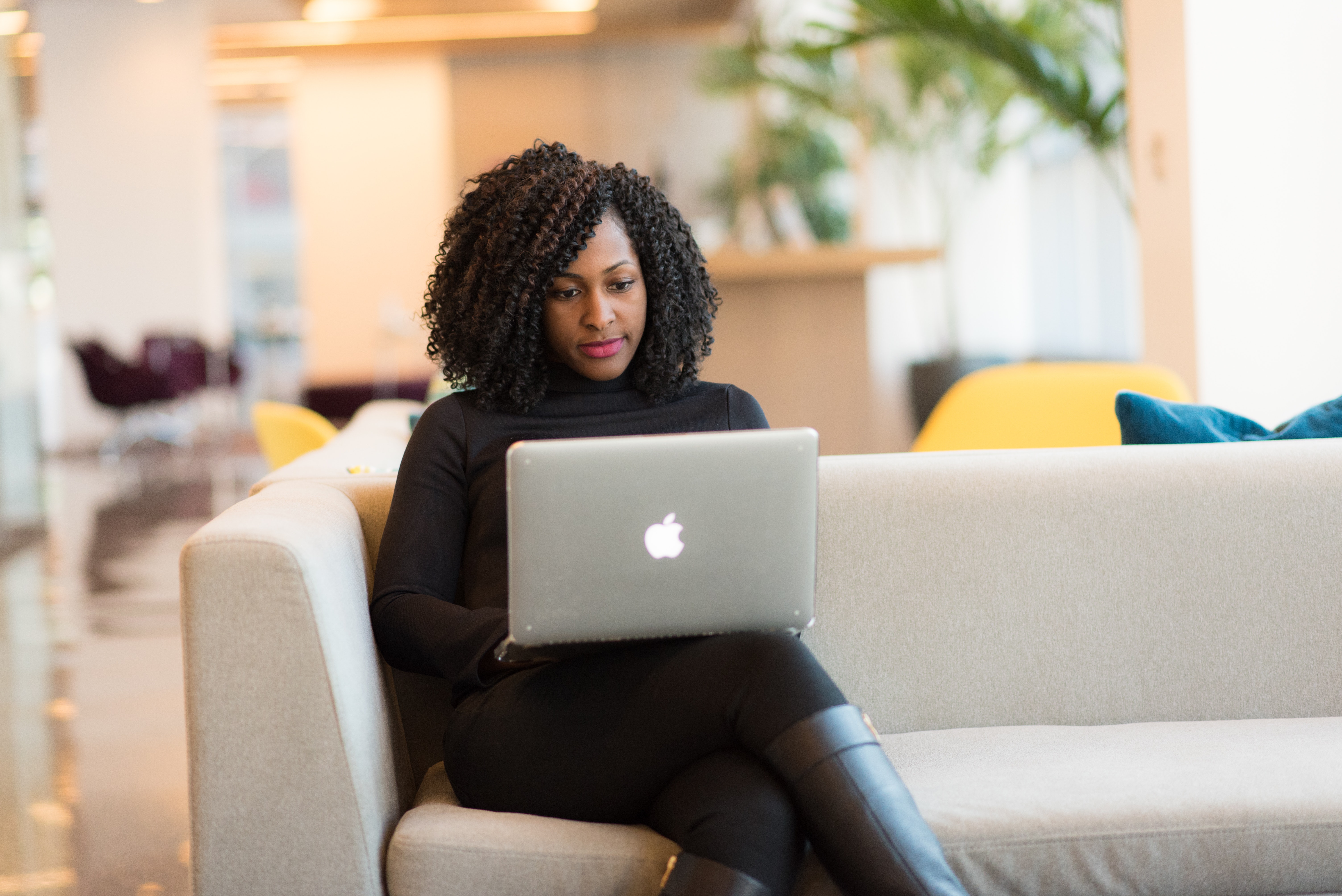 A woman sitting on a couch working on her laptop